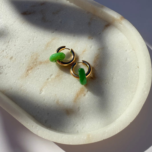 Gold and chrysoprase hoop earrings on marble stone