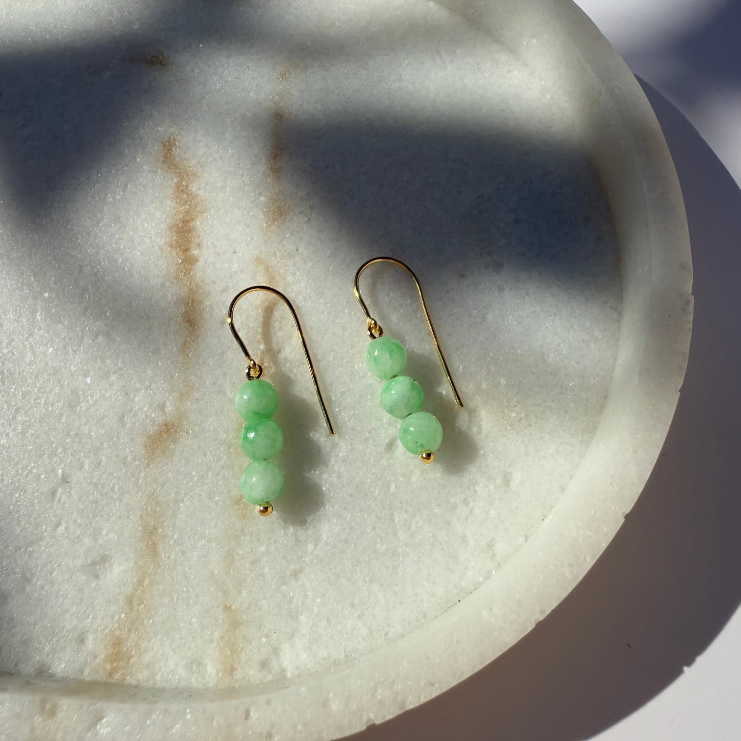 Pair of chrysoprase beaded earrings on a marble surface