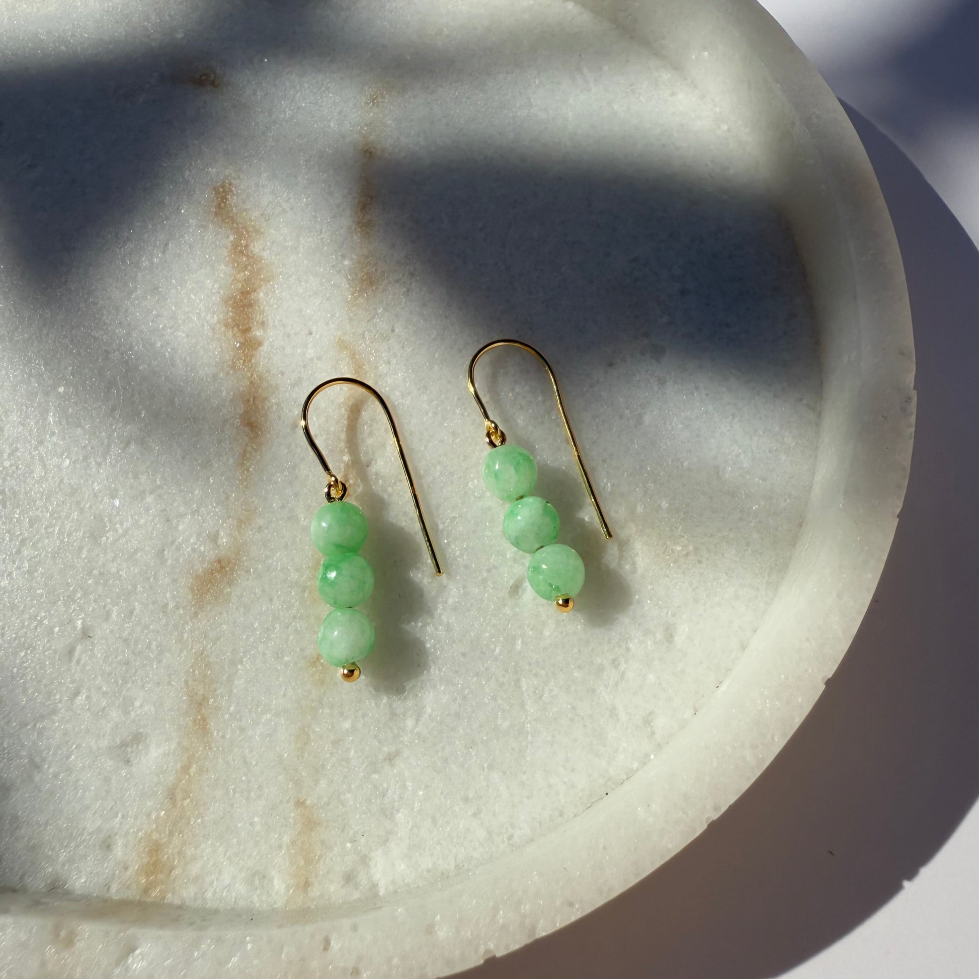 Pair of chrysoprase beaded earrings on a marble surface
