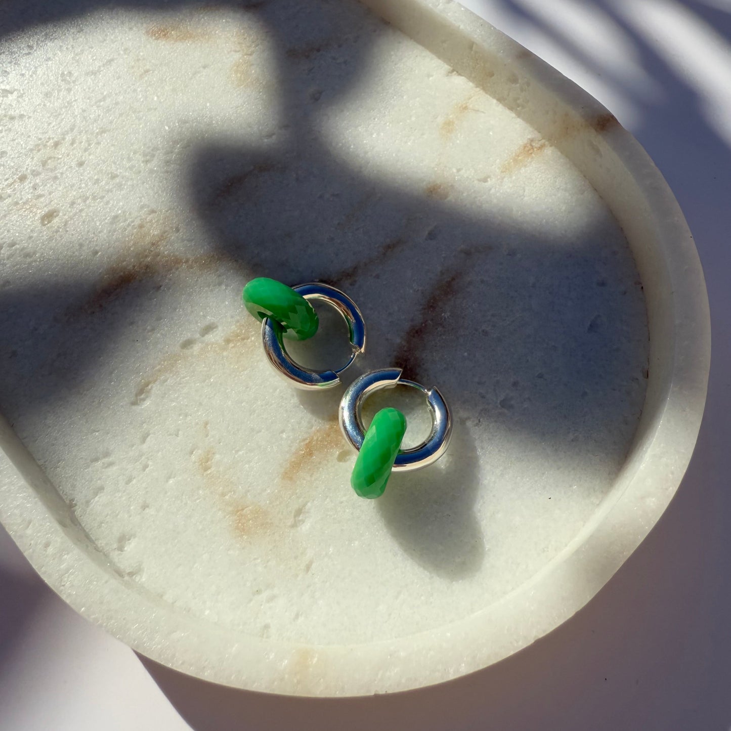 Pair of hoop earrings with chrysoprase and silver on a marble stone 