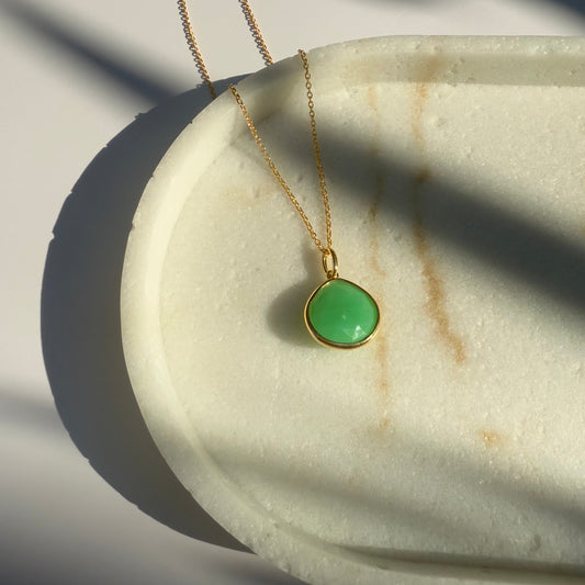 Gold chrysoprase  necklace with a pear pendant on a marble surface