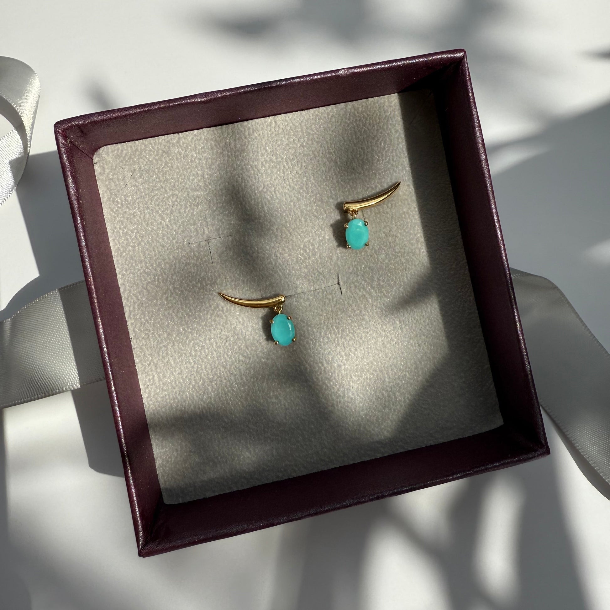 Pair of gold earrings with turquoise stones in a jewelry box