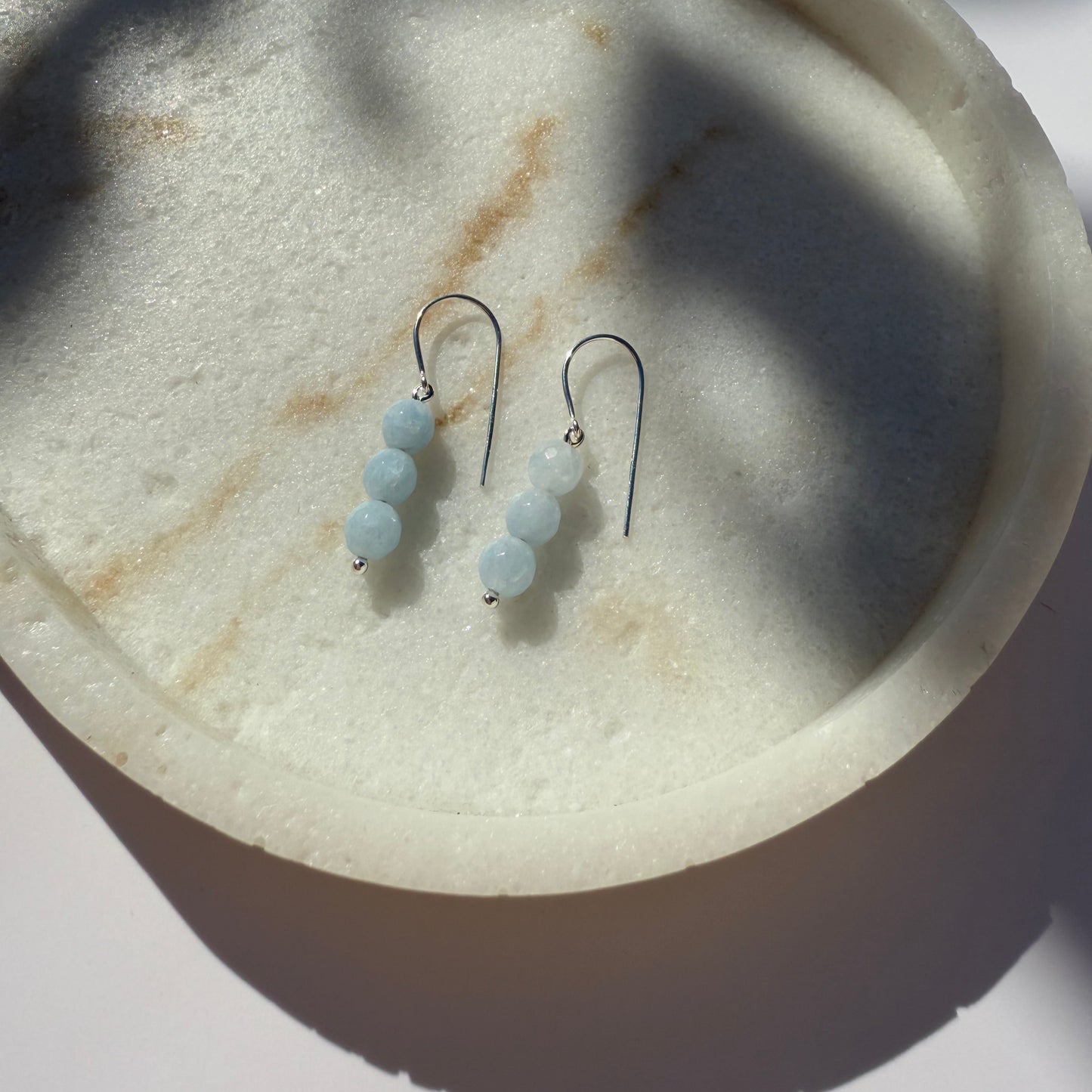 Pair of silver aquamarine beaded earrings on a marble surface