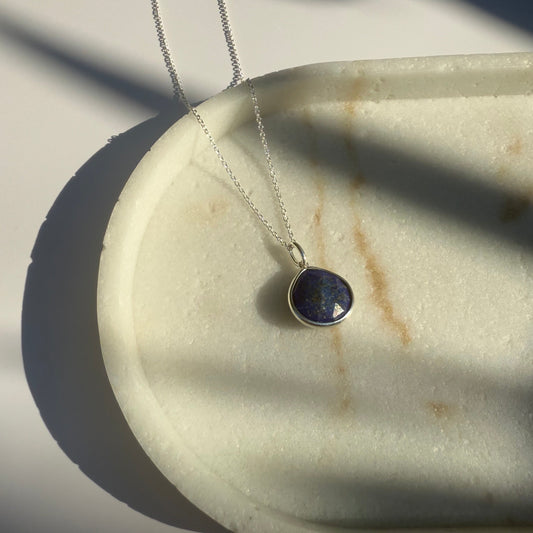 Silver lapis lazuli  necklace with a pear pendant on a marble surface