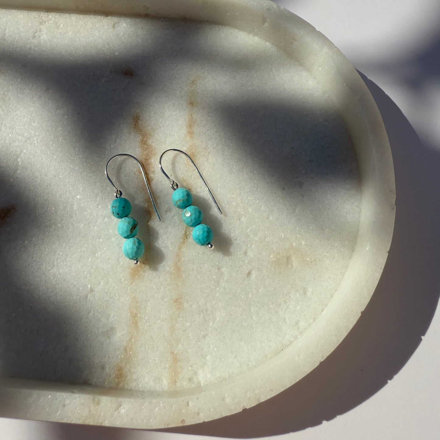 Turquoise beaded earrings on a marble surface