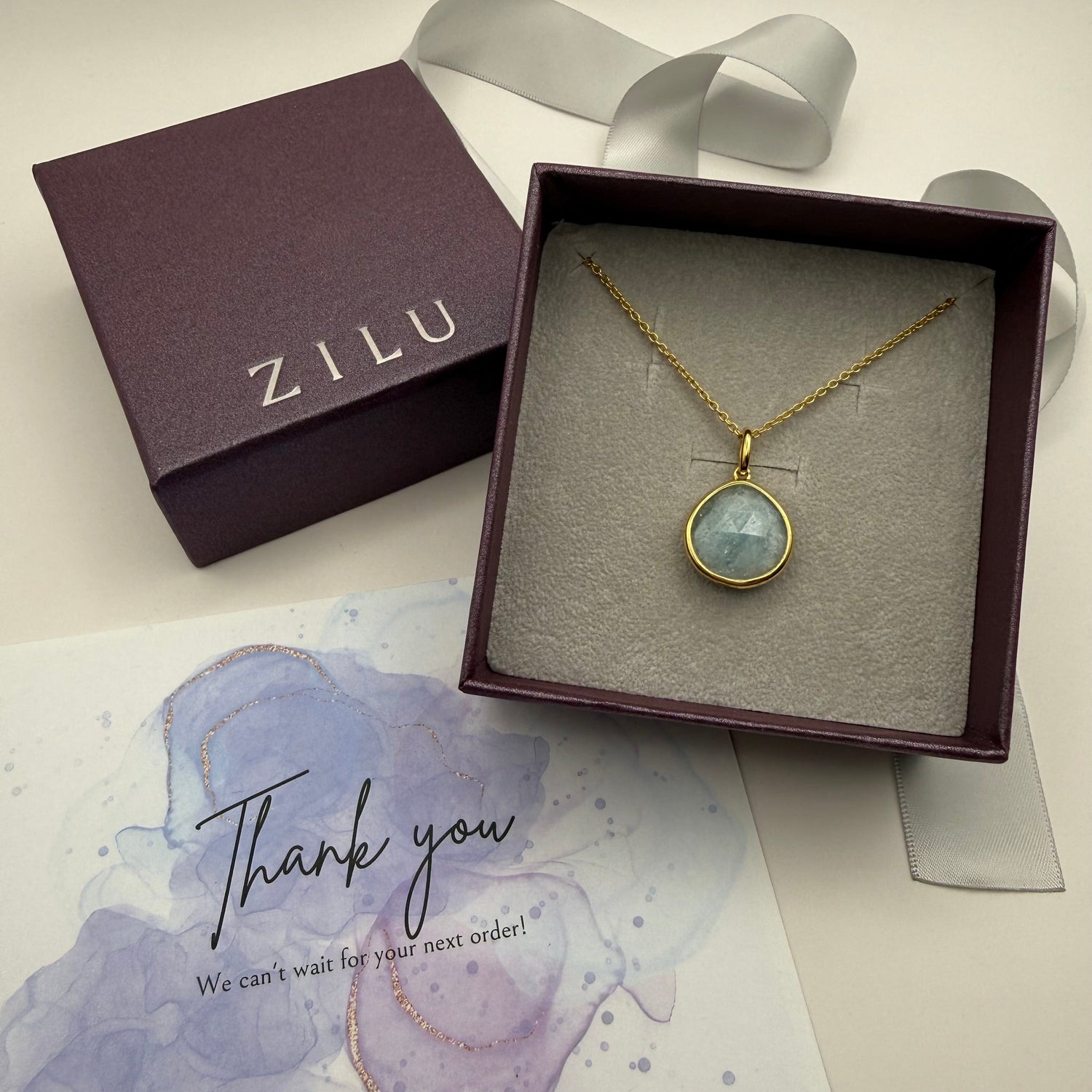 Necklace with pendant in ZILU box on a light background with a thank you note